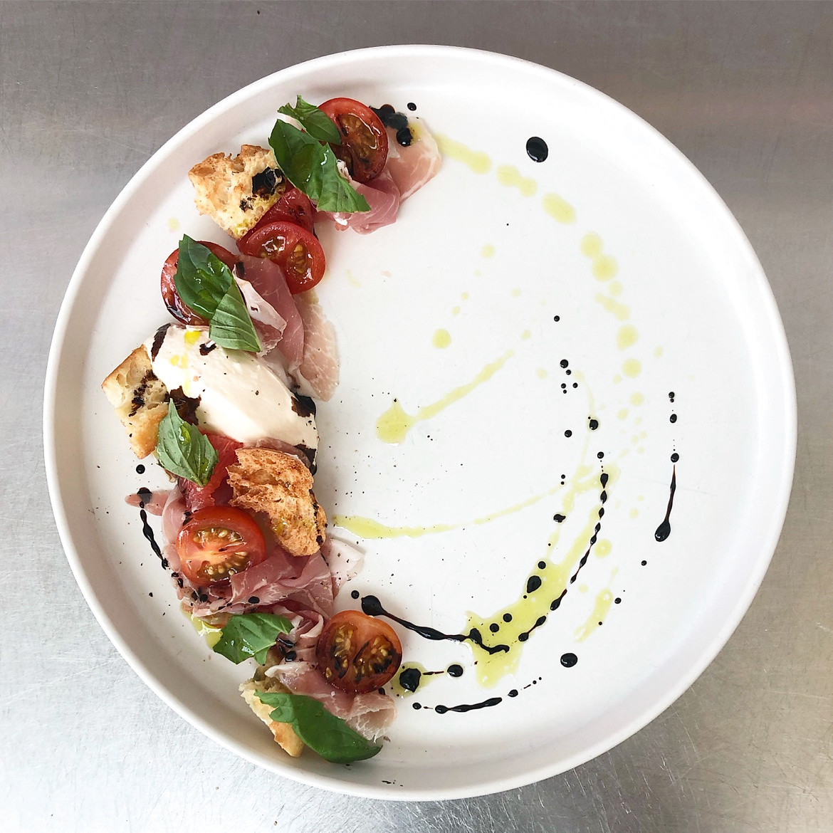 Burrata servie avec prosciutto, tomates fraîches et basilic