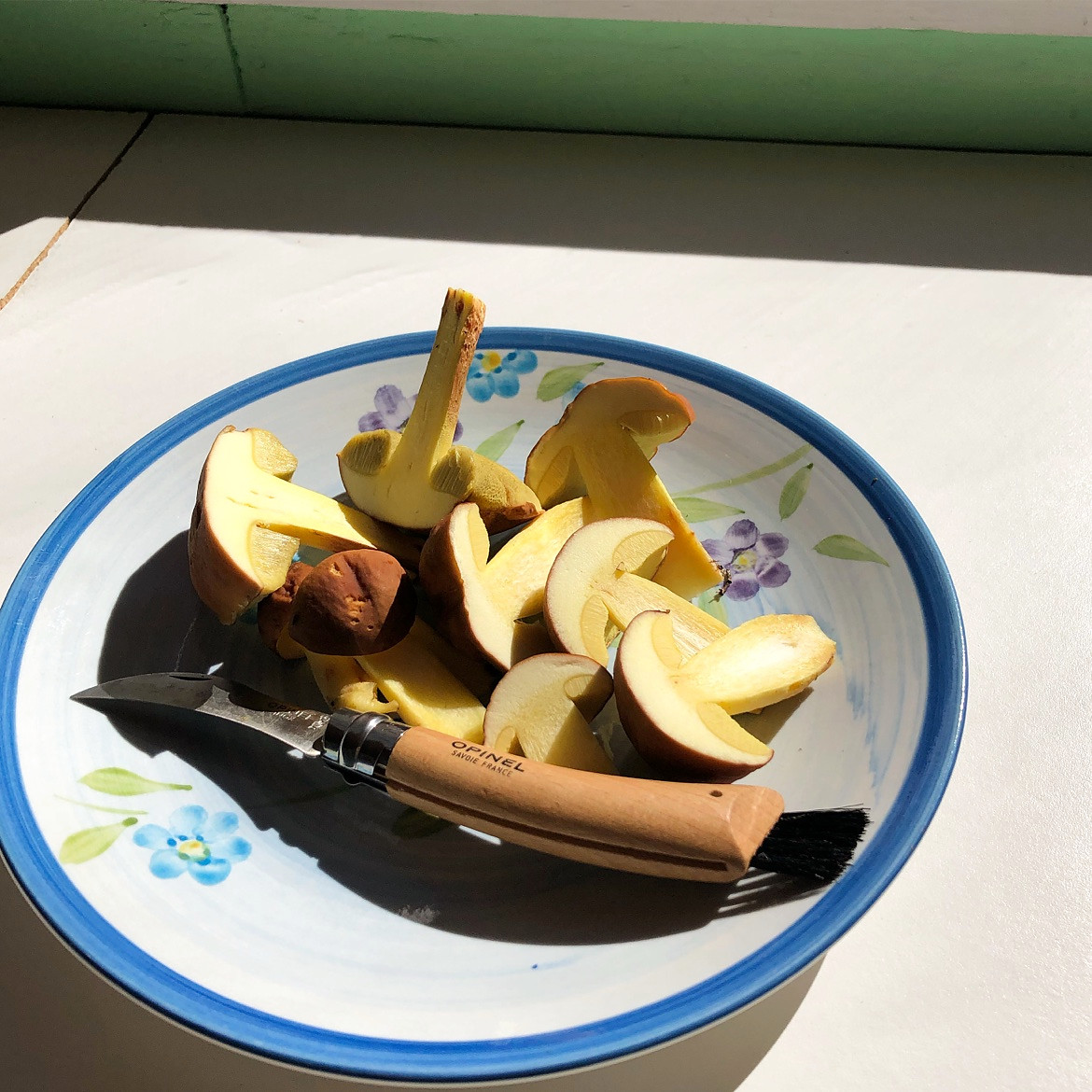 Champignons frais émincés sur une planche avec un couteau Opinel