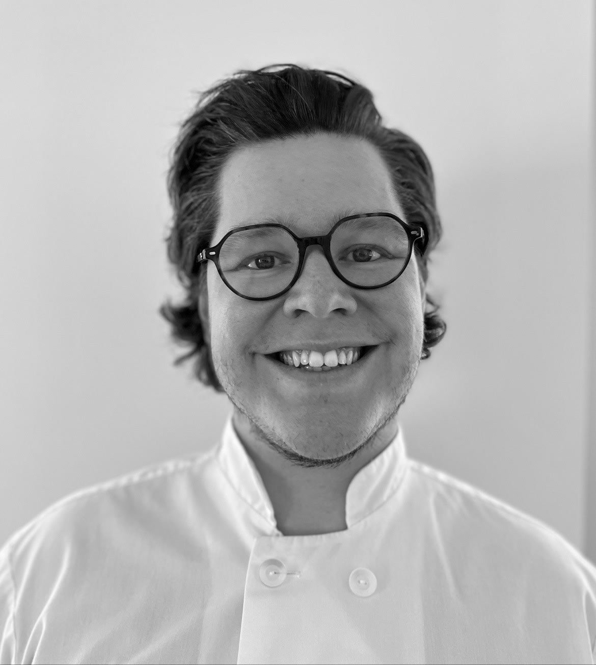 Portrait souriant en noir et blanc de Michaël Brown avec lunettes et veste de chef